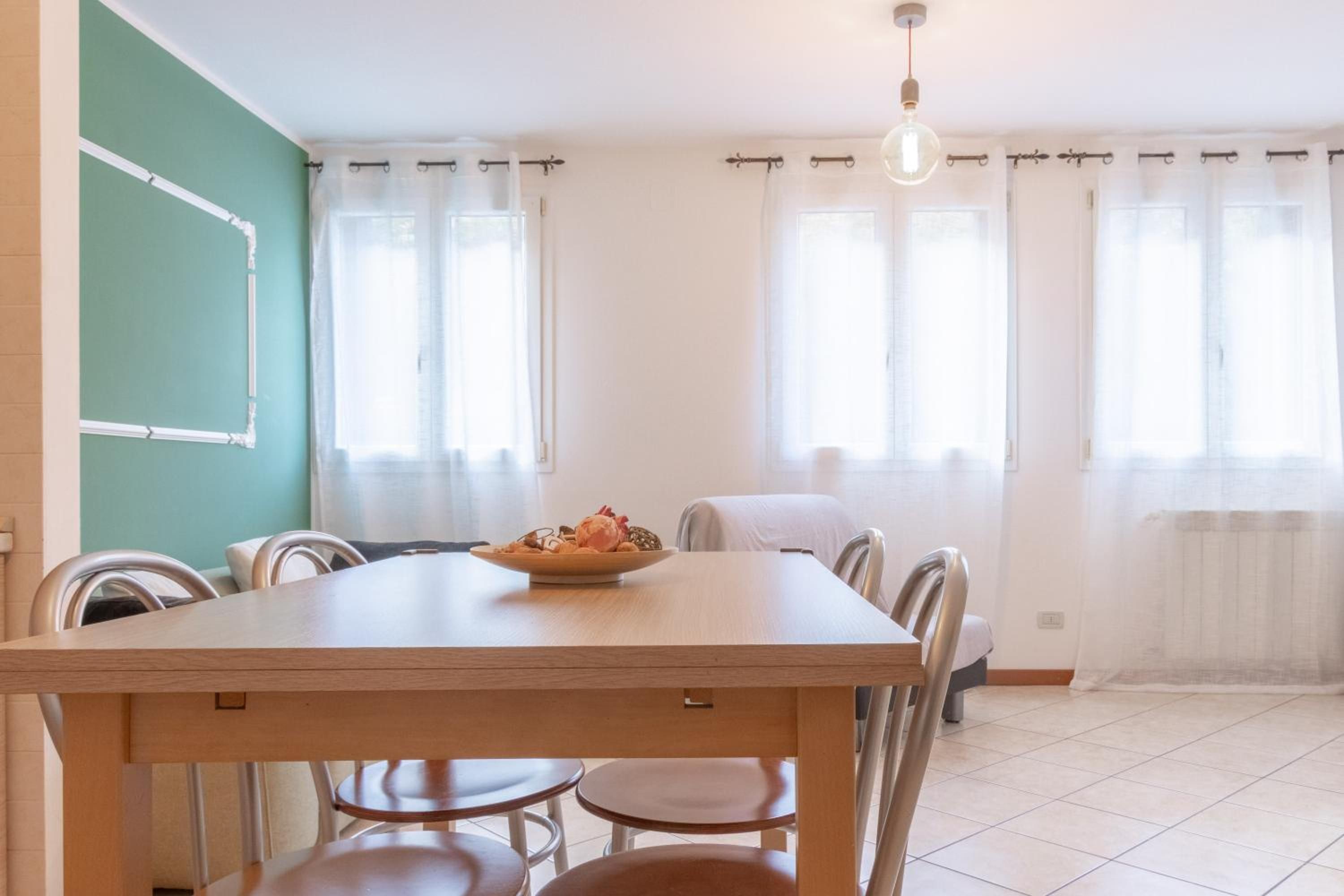 A dining area with a wooden table, chairs, and a bowl of fruit.