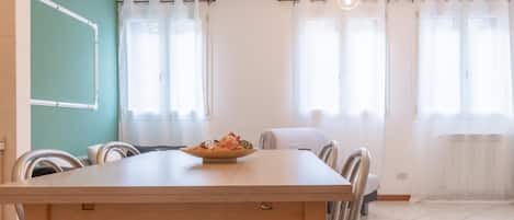 A dining area with a wooden table, chairs, and a bowl of fruit.