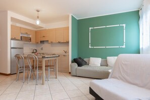 A compact living space with a kitchenette, a dining area with chairs, and a sofa. - Residence Rialto (Trieste)