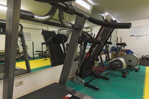 A gym with exercise equipment, a mirrored wall, and a green exercise mat. - Residence Rialto (Trieste)