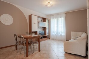 A living room with a dining table, chairs, a sofa, a TV, and a cabinet. - Residence Rialto (Trieste)