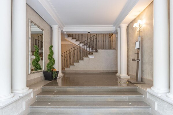 A grand staircase leading to a reception area with a polished floor and decorative plants. - Residence Rialto (Trieste)