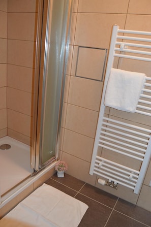 A bathroom with a shower, a white towel rack, and a small potted plant. - Hotel Aréna (Prague)