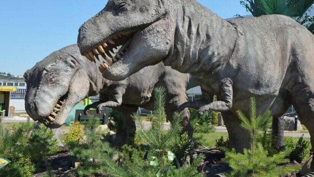 A dinosaur statue in a landscaped area with a building in the background. - Hotel Aréna (Prague)