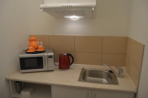 A kitchenette with a microwave, kettle, and orange teapot on the counter. - Hotel Aréna (Prague)