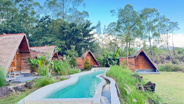 Ein Resort mit Holzhütten, einem Schwimmbad und üppiger Vegetation.