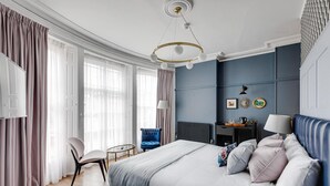 Een slaapkamer met een bed, een stoel, een bureau en een radiator.