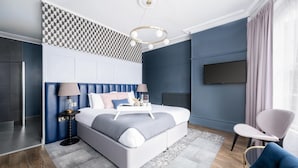 Een moderne slaapkamer met een bed, nachtkastjes, een lamp, een stoel en een televisie.
