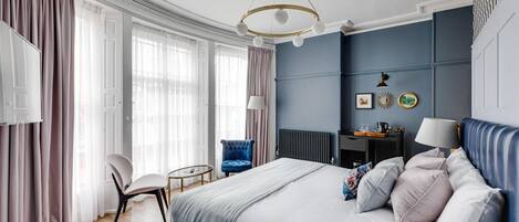 A bedroom with a bed, a chair, a desk, and a radiator.