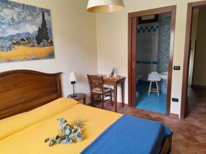 A hotel room with a bed, a desk, a chair, a lamp, and a painting on the wall. - Poggio Desto Bed & Breakfast (Quarrata)