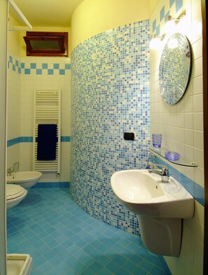 A bathroom with a white sink, two toilets, a blue-tiled wall, and a mirror. - Poggio Desto Bed & Breakfast (Quarrata)