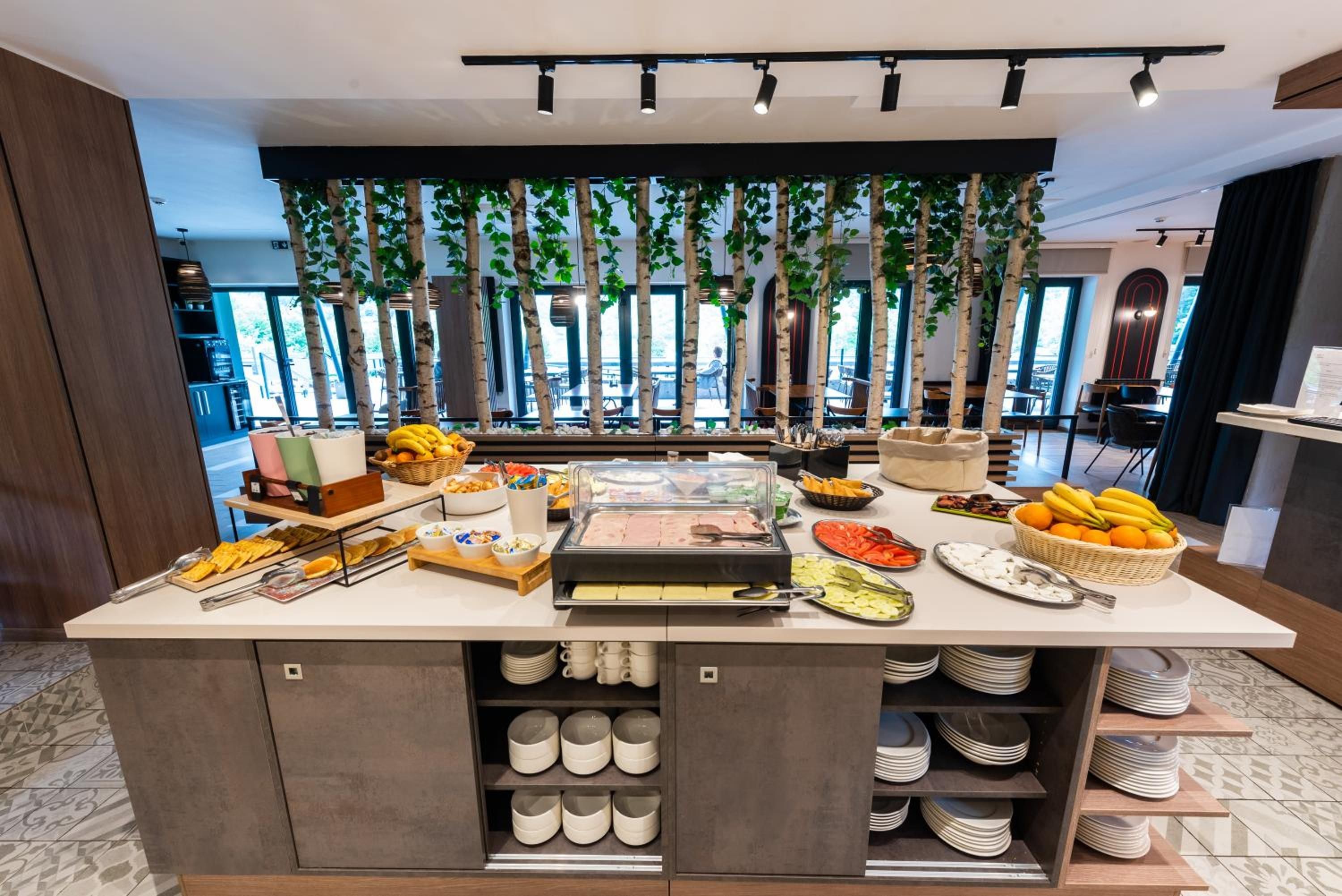 Un buffet proposant une variété de plats, ainsi qu’une vitrine réfrigérée, le tout dans un décor moderne avec vue sur l’extérieur.