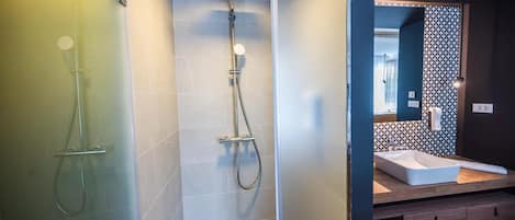 Un baño moderno con cabina de ducha de vidrio, ducha independiente y tocador con lavabo y espejo.