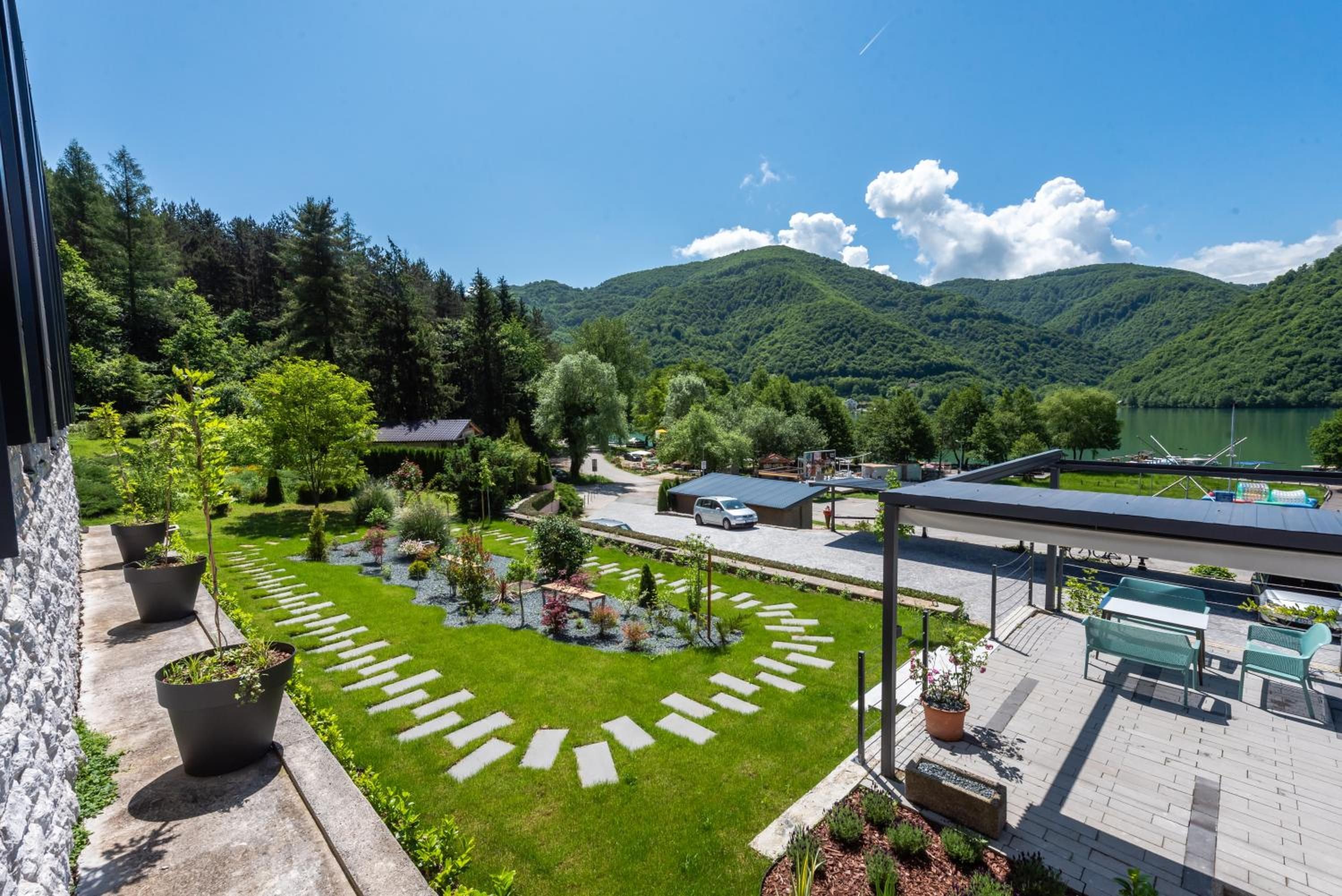 Un jardin aménagé offrant une vue dégagée sur un lac et des montagnes en arrière-plan.