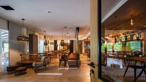 Tilava ravintola, jossa on puulattiat, useita oleskelualueita ja katosta roikkuvia riippuvalaisimia.