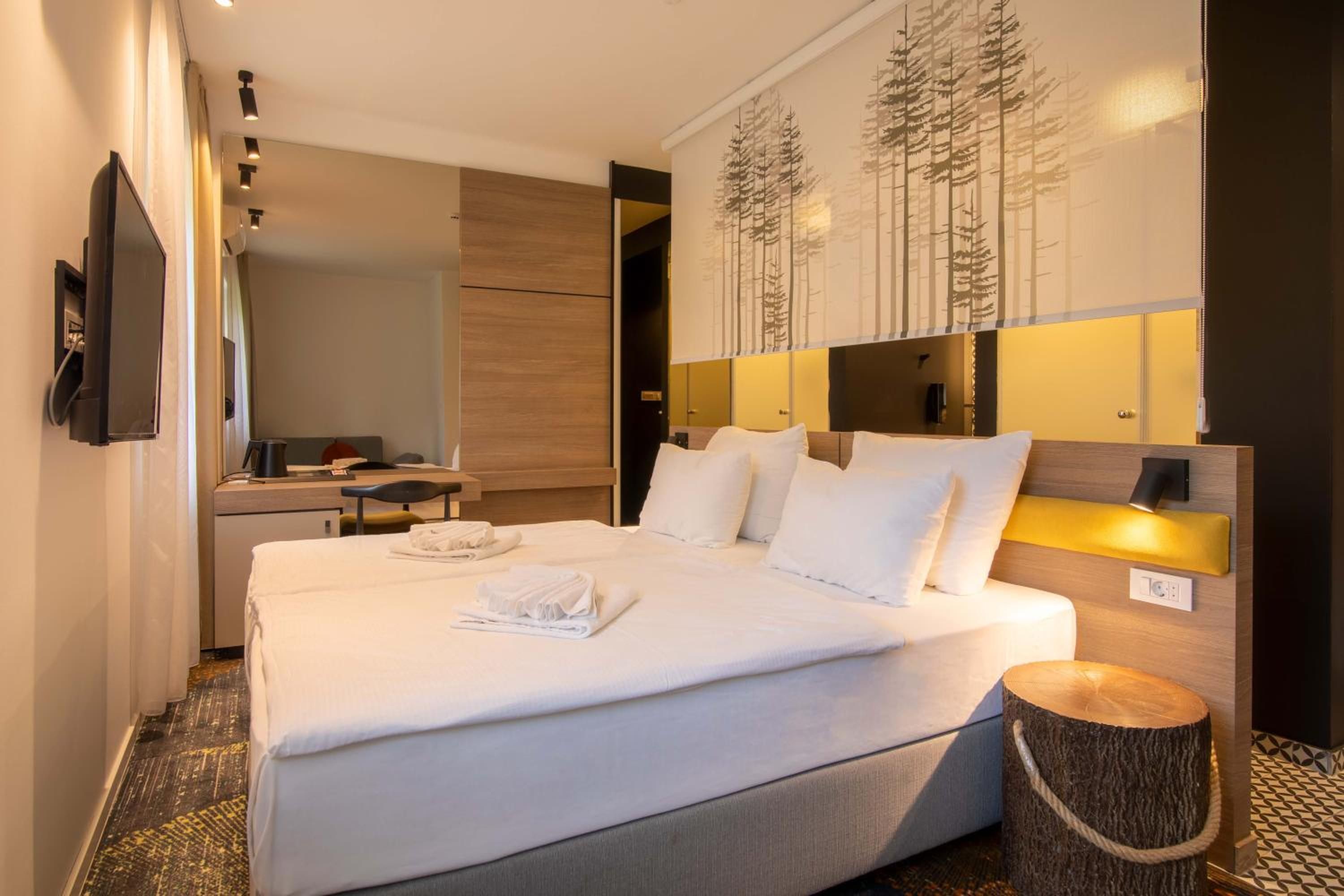 Une chambre d’hôtel avec un lit, une table de chevet et un miroir.