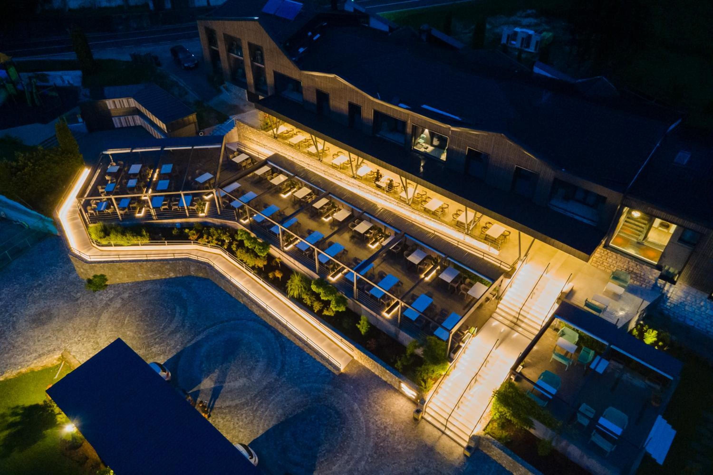 Ein Luftbild eines Hotels mit mehreren Stockwerken, Außenbereichen zum Sitzen und einem Schwimmbecken.