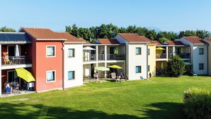 Une rangée d’immeubles à étages, dotés de balcons, de terrasses extérieures et d’une pelouse bien entretenue.