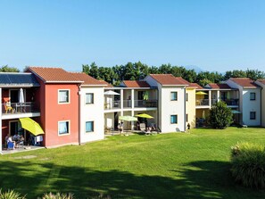 Eine Reihe mehrstöckiger Gebäude mit Balkonen, Außenbestuhlung und einem gepflegten Rasen.