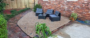 An outdoor seating area with wicker furniture and a brick wall backdrop.