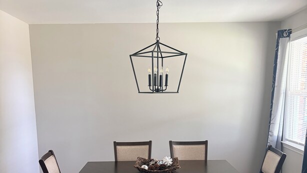 Ein Esszimmer mit einem dunklen Holztisch, vier Stühlen, einer Bank und einer Pendelleuchte.