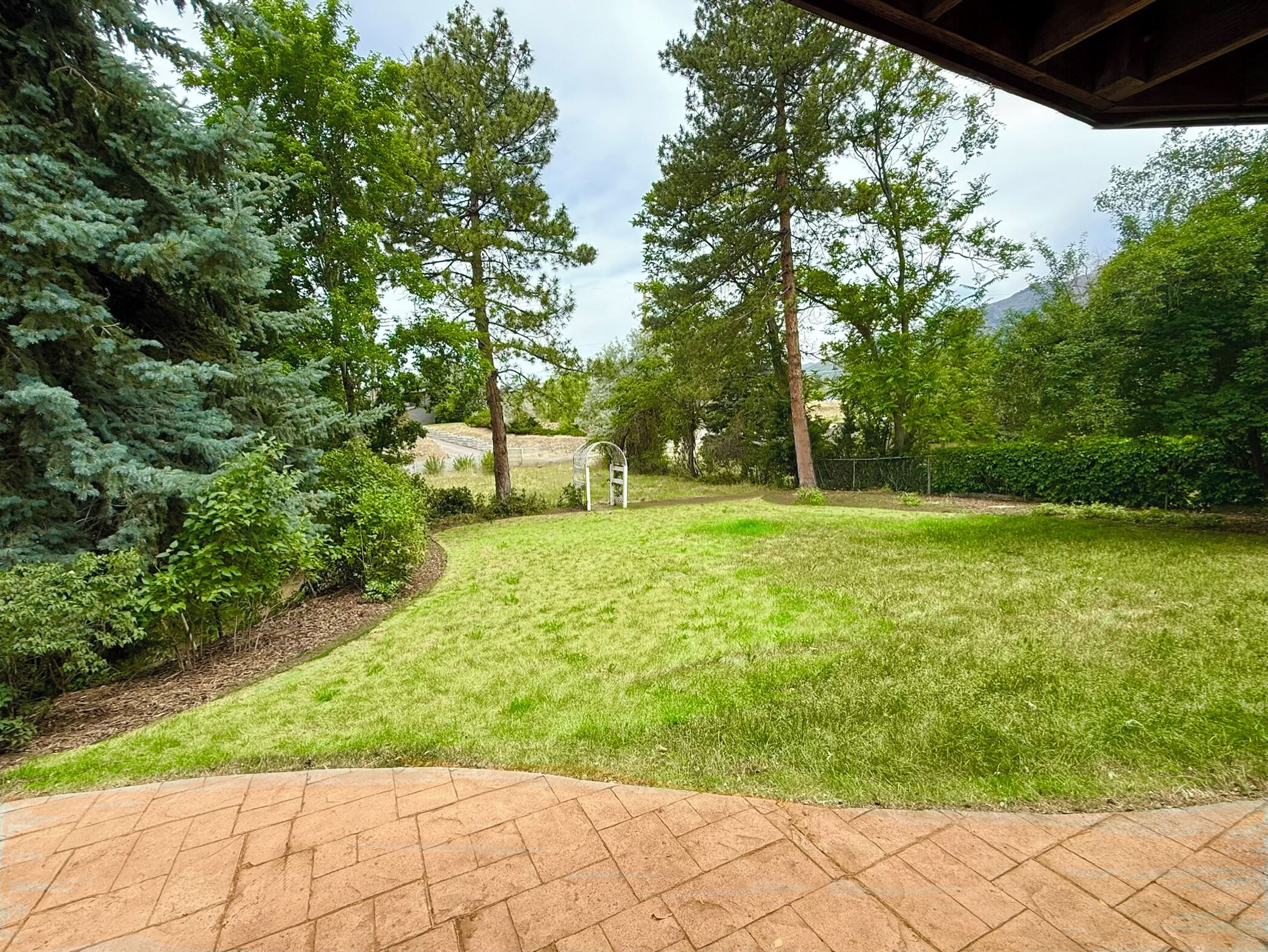 A well-maintained lawn with a brick pathway leading to a white gazebo.