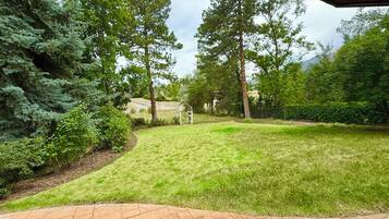 A well-maintained lawn with a brick pathway leading to a white gazebo.