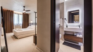 A modern hotel room with a bed, a ceiling fan, a bathroom with a sink and mirror, and a view of the outside. - Casa Sud Luxury 2BR Apartment (Vlorë)