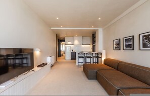 Ein modernes Wohnzimmer mit Flachbildfernseher, einer Couch und einem Essbereich mit Stühlen.