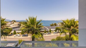 A coastal view with a road, parked cars, and buildings with solar panels. - Casa Sud Luxury 2BR Apartment (Vlorë)