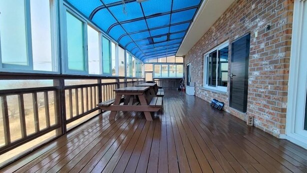 Eine Terrasse im Freien mit Holzboden, Picknicktischen und einem blauen, ausziehbaren Dach.