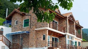 A two-story brick building with a balcony, a staircase, and a solar panel.