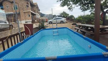 A rectangular swimming pool with a ladder, surrounded by a wooden deck.