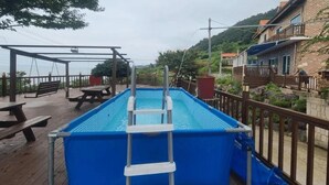 Ein rechteckiger Pool mit einer Leiter, umgeben von einer Holzterrasse mit Picknicktischen.