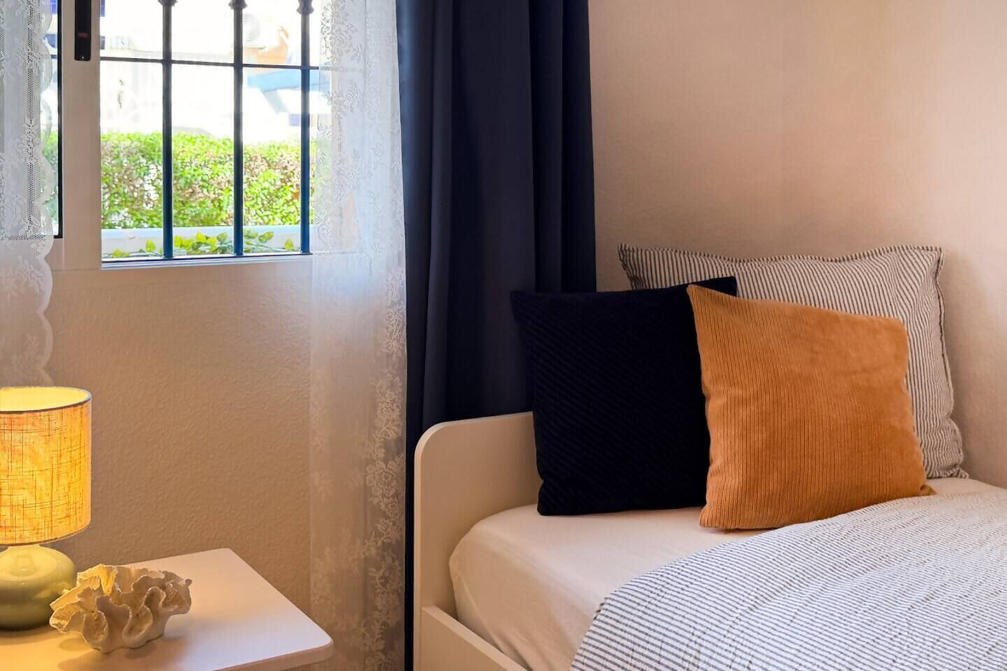 A hotel room with a bed, a nightstand with a lamp, and a window with curtains.