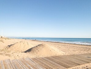 A beach with a wooden boardwalk leading to the shore, clear skies, and a calm sea. - Pink Buganvilla Lodging (Torrevieja)