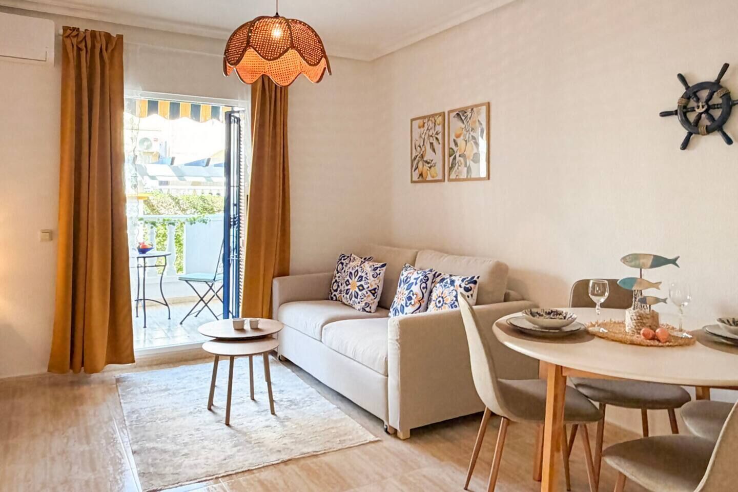Un salon moderne comprenant un canapé, une table à manger avec des chaises, un luminaire suspendu et une vue sur l’extérieur.