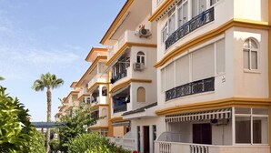 Uma fileira de edifícios altos com varandas, aparelhos de ar condicionado e céu claro.