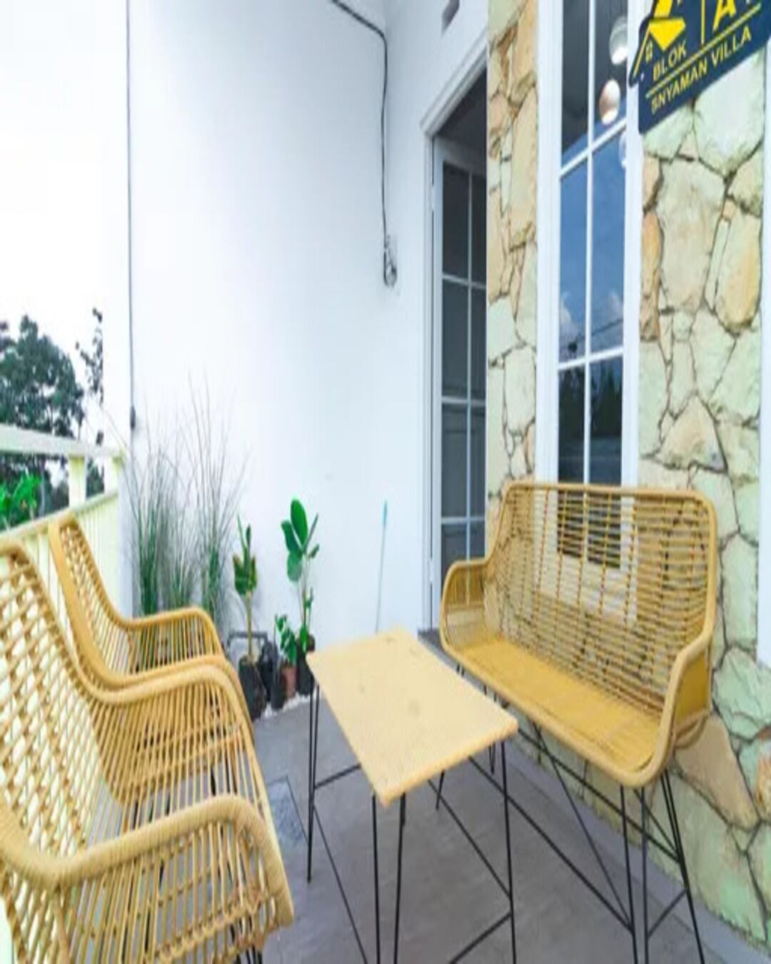An outdoor seating area with wicker furniture and a stone wall.