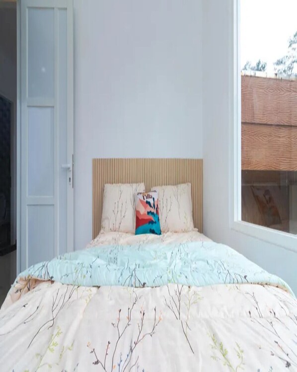 A bedroom with a bed, a window, and a door.