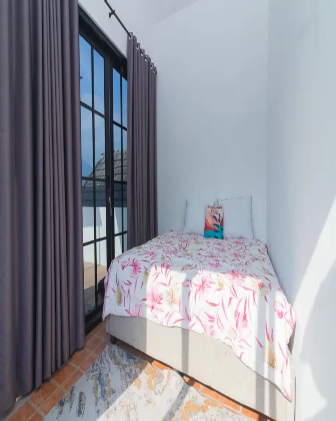 A bedroom with a bed, curtains, and a window.