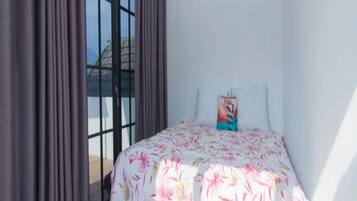 A bedroom with a bed, curtains, and a window.