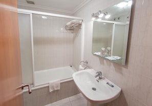 Une salle de bain avec une baignoire, un lavabo et un miroir.