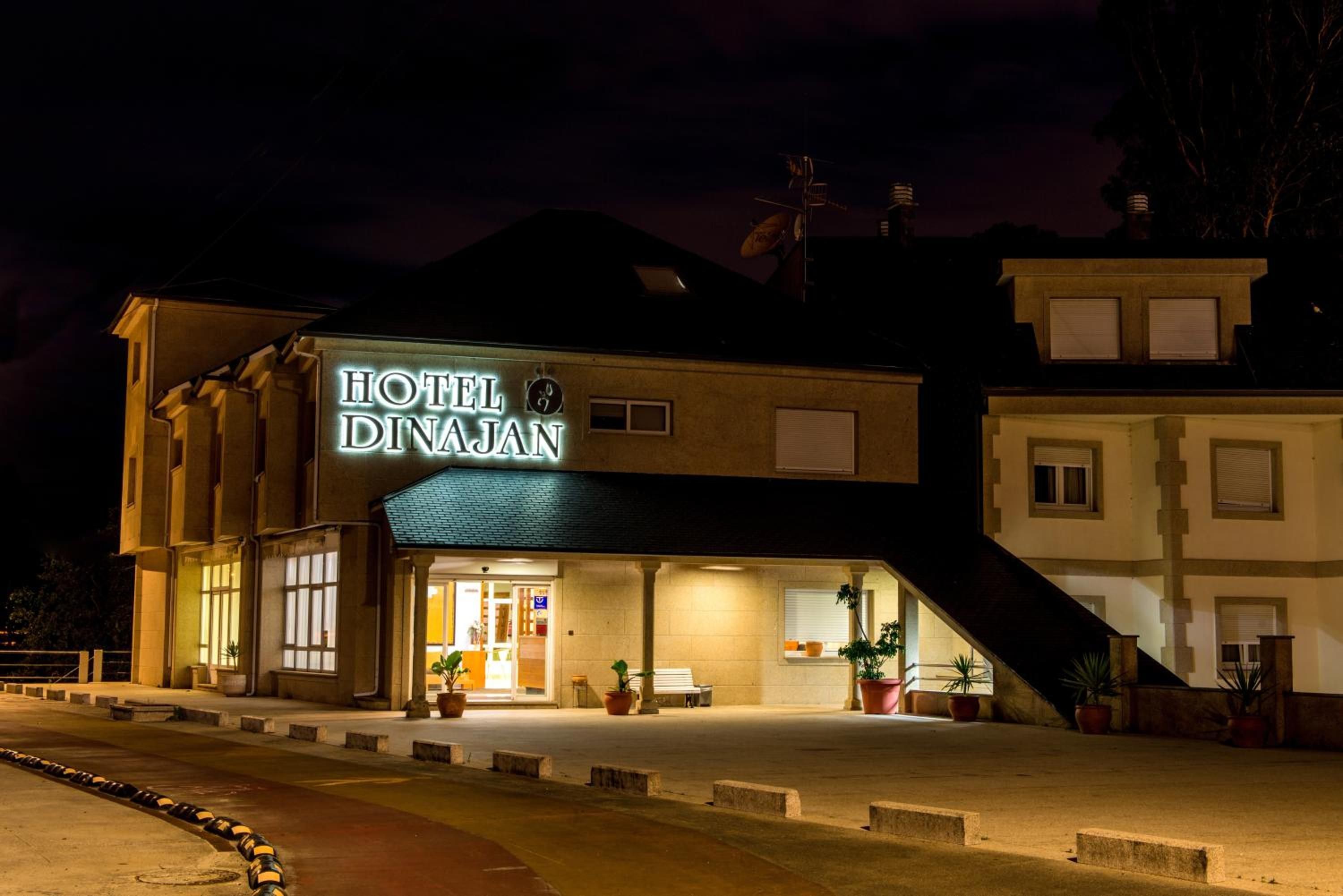 Un hotel con un letrero iluminado y llamativo, una entrada principal y una escalera que lleva a ella.