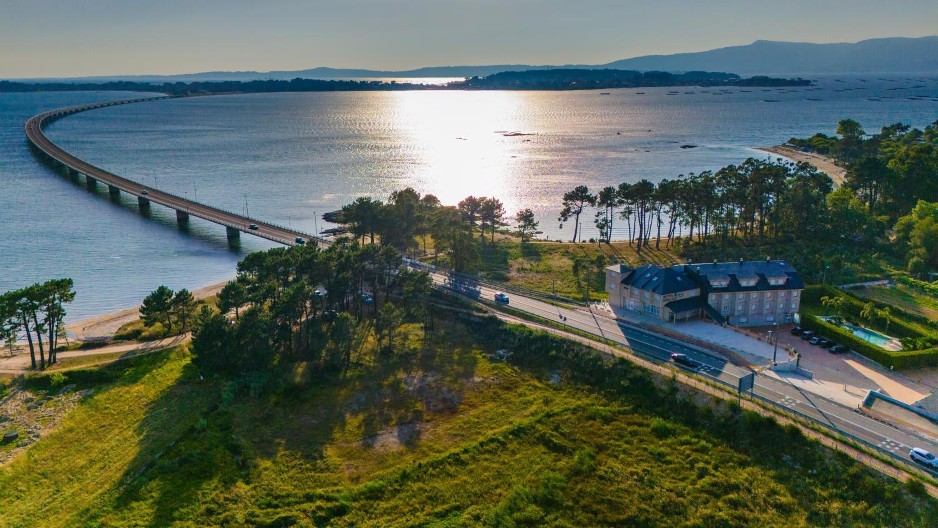Una carretera costera con un puente, una playa y un edificio con piscina.