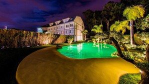A hotel with a swimming pool, surrounded by trees and a well-lit building. - Hotel Dinajan (Vilanova de Arousa)