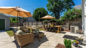 Ein Hinterhof mit Terrassenausstattung, einem Tisch und Sonnenschirmen.