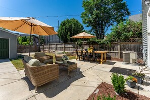 A backyard patio with outdoor furniture, a table, and umbrellas. - Lavender Hill Skyline - Sleeps 12 - City Views (Milwaukee)