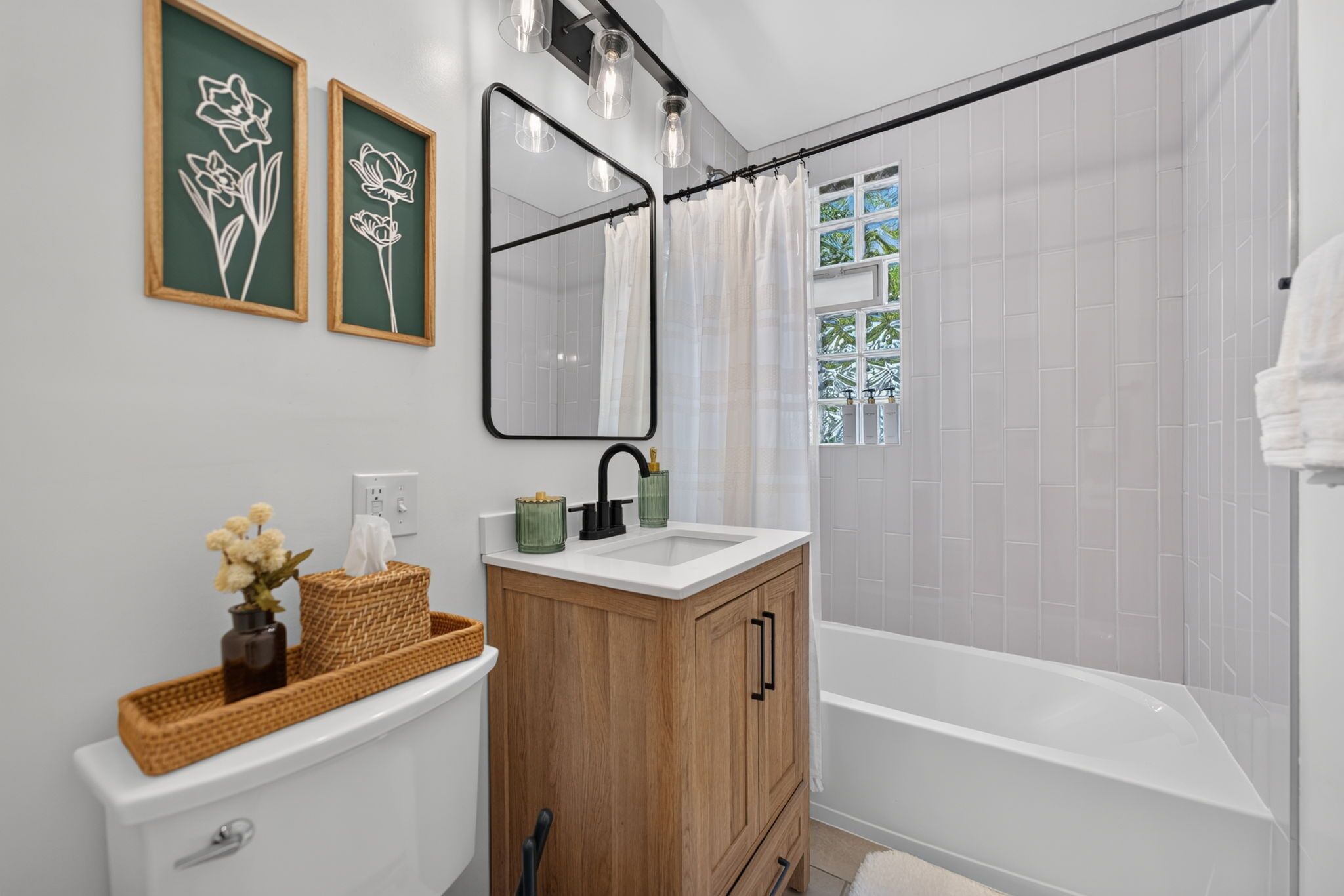 A bathroom with a white sink, wooden vanity, and a bathtub.