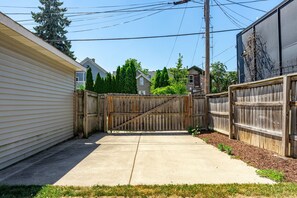 A residential backyard with a wooden fence, a concrete driveway, and houses in the background. - Lavender Hill Skyline - Sleeps 12 - City Views (Milwaukee)
